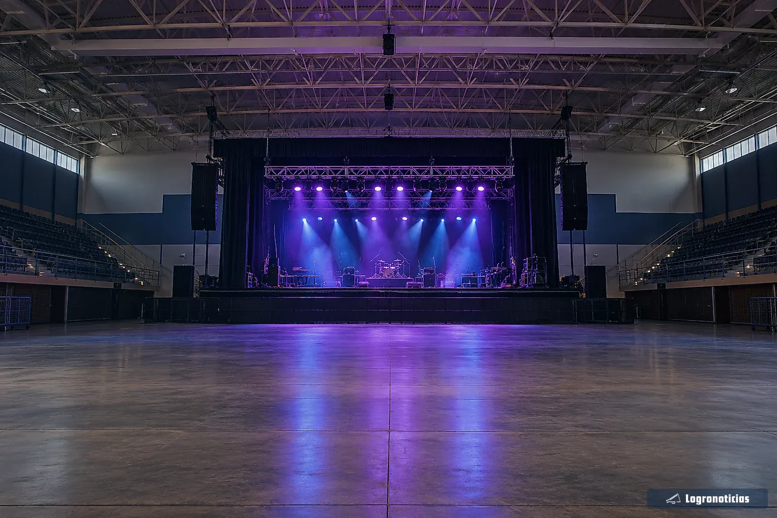 Pista de un pabellón con escenario iluminado antes de un concierto