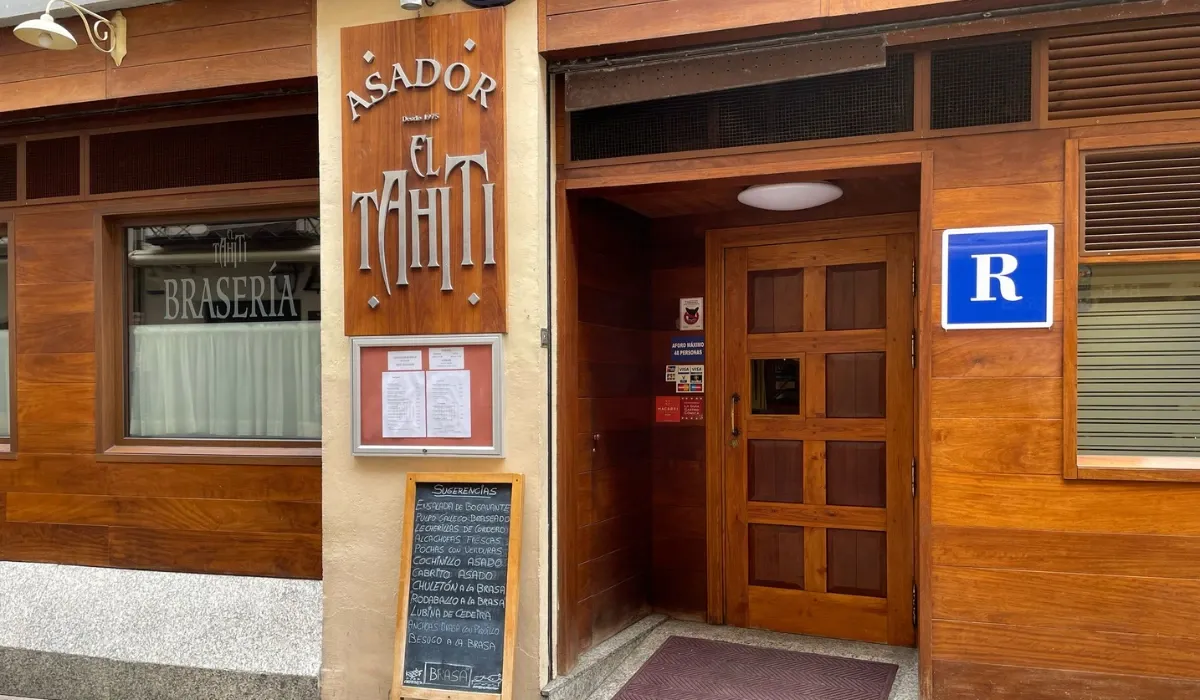 Fachada de madera del Asador El Tahití con pizarra de sugerencias en la puerta