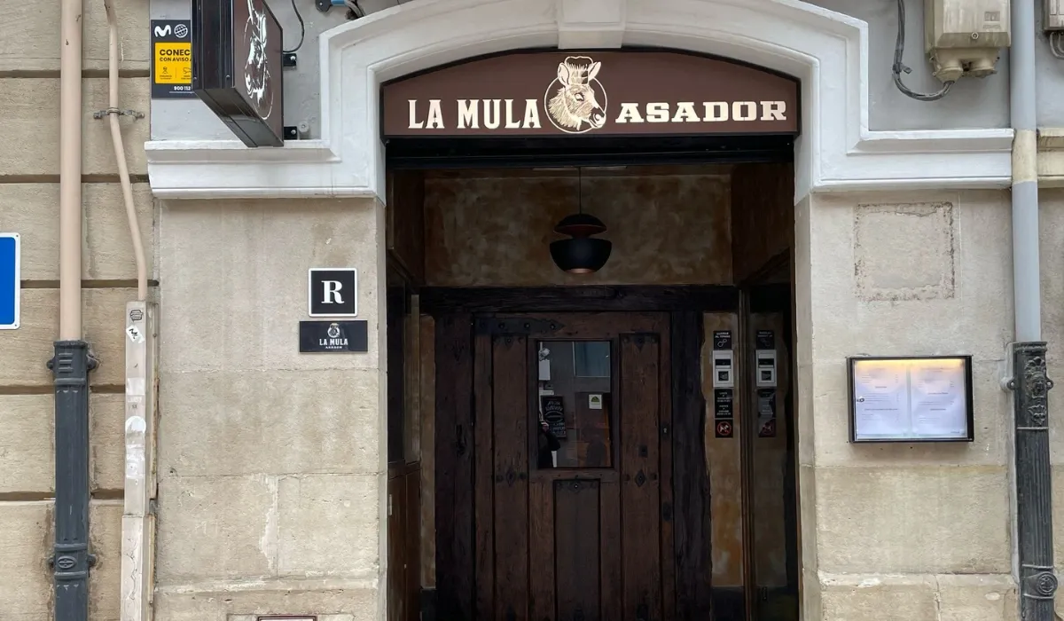 Entrada de Asador La Mula con rótulo marrón y puerta de madera antigua