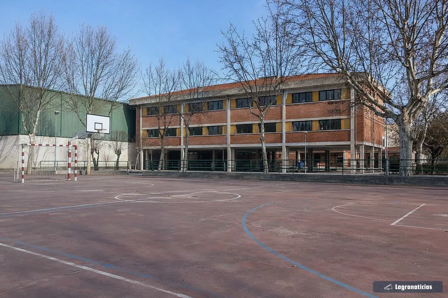 Patio de colegio vacío en vacaciones con las porterías y la canasta