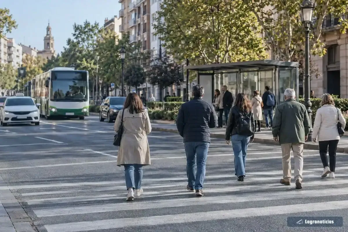Peatones cruzando por un paso de cebra junto a una parada de autobús