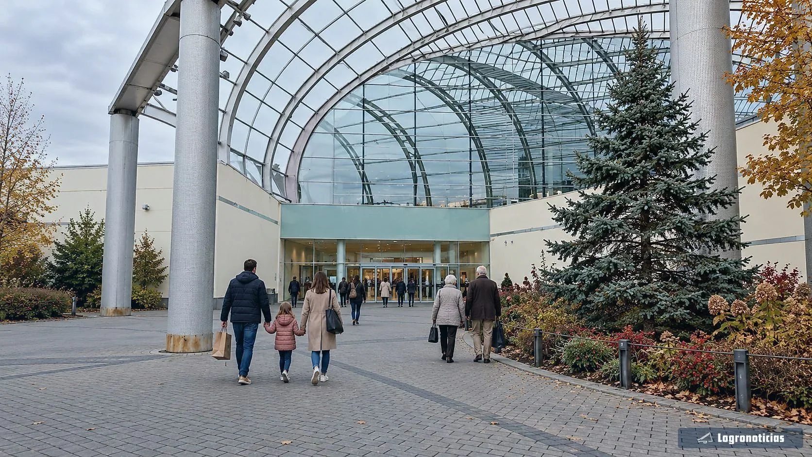 Gente entrando con bolsas en un centro comercial bajo una cubierta acristalada
