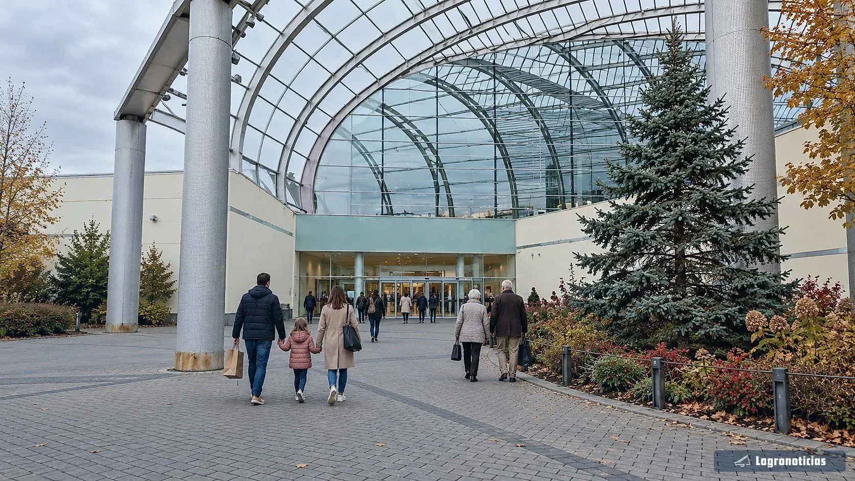 Gente entrando con bolsas en un centro comercial bajo una cubierta acristalada