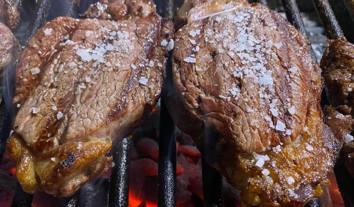 Dos chuletones con sal gruesa sobre la parrilla y brasas al rojo