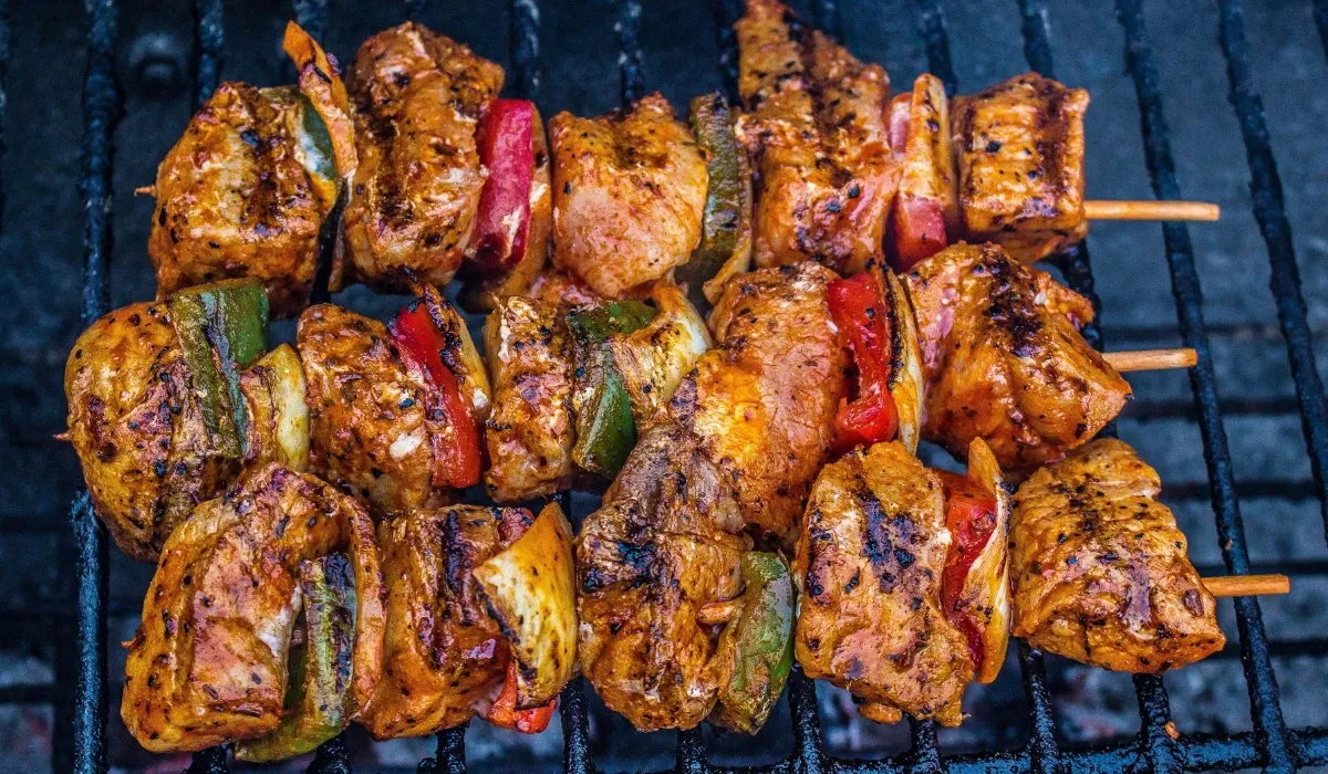 Brochetas de carne adobada con pimiento rojo y verde sobre una parrilla