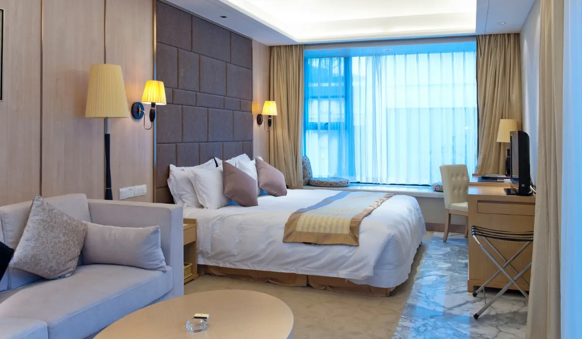 Habitación de hotel amplia con cama doble, sofá y escritorio