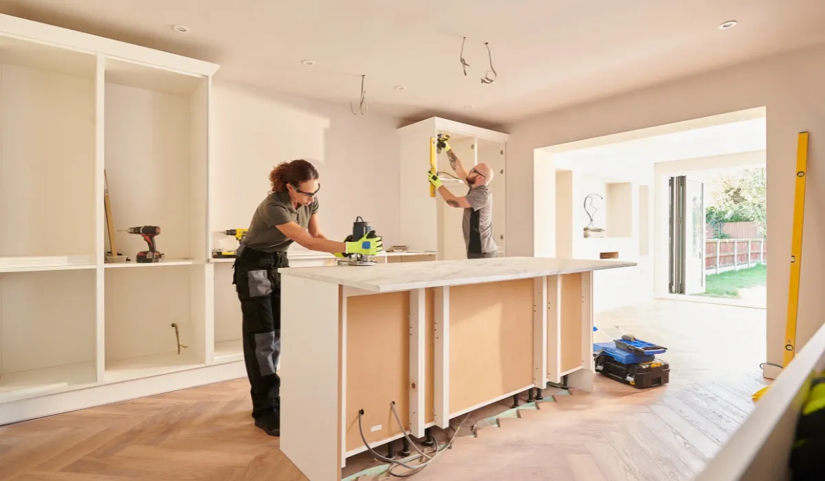 Dos montadores instalan una isla de cocina y un armario en una vivienda en obras