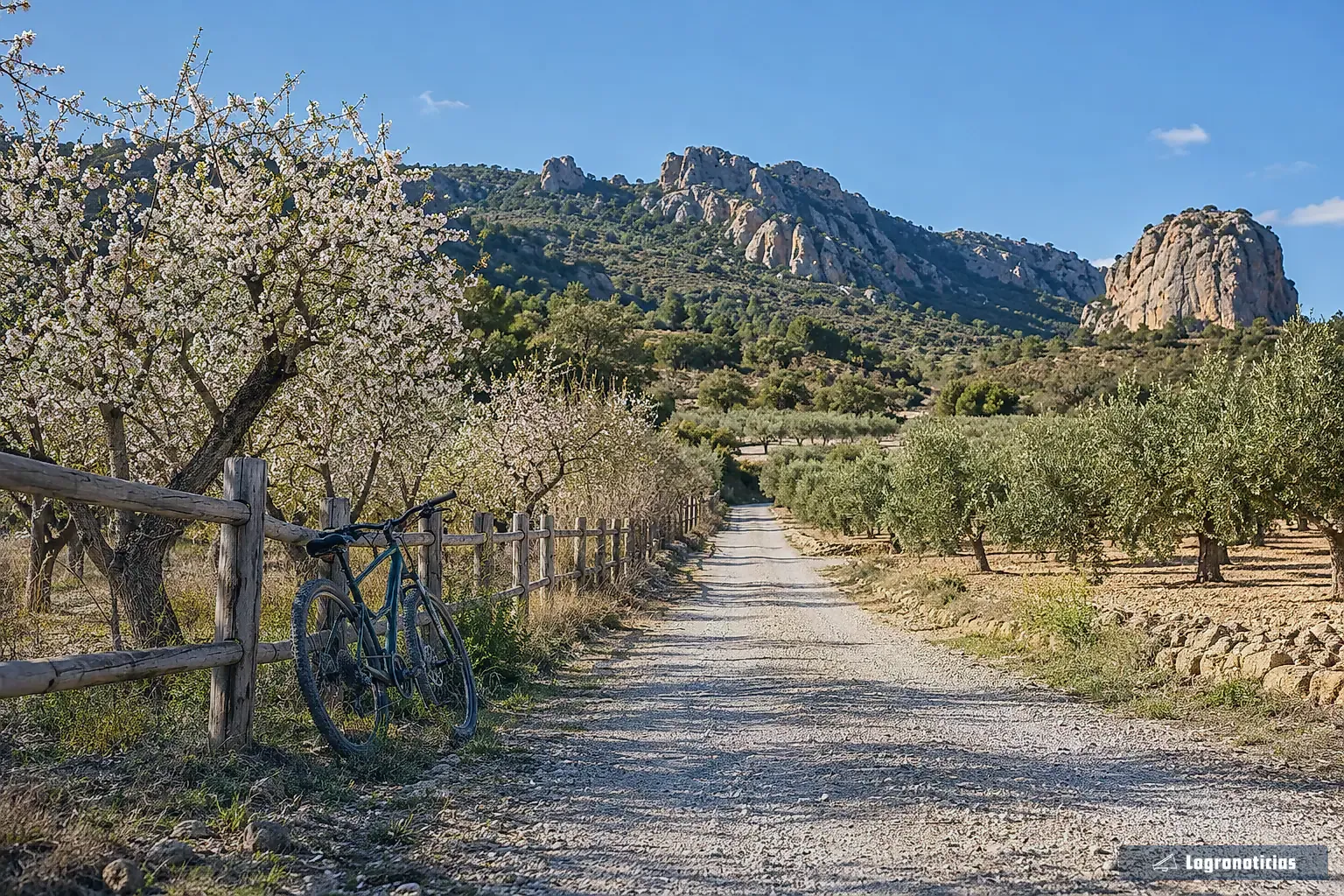 Camino de grava de una antigua vía de tren entre huertas y peñas