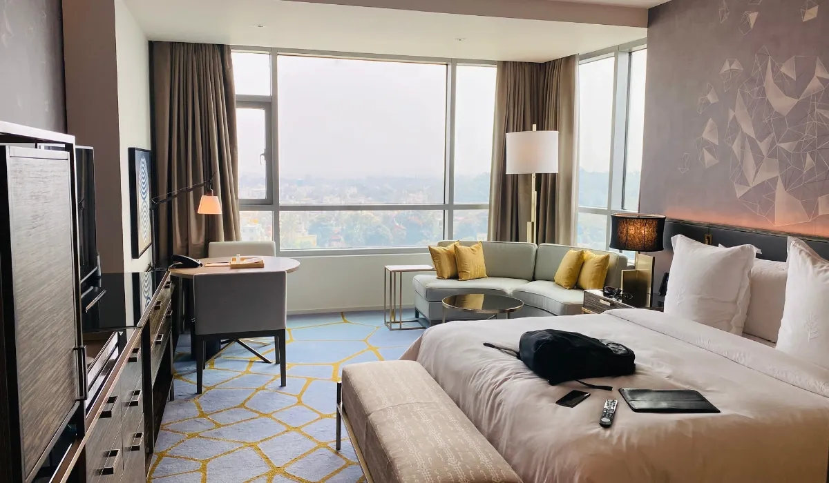 Habitación de hotel con cama doble, sofá y ventanal a la ciudad