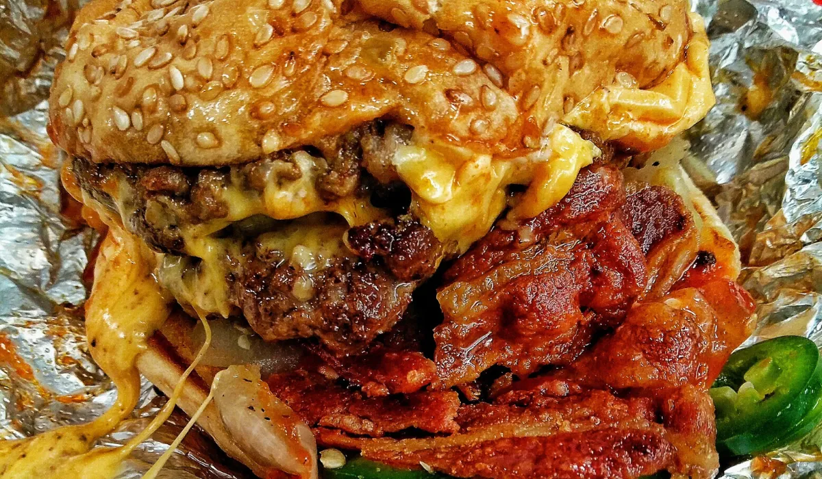 Hamburguesa doble con queso fundido, beicon crujiente y jalapeños sobre papel de aluminio