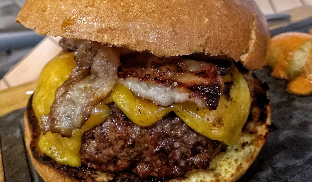 Hamburguesa gruesa con queso cheddar fundido y panceta a la plancha