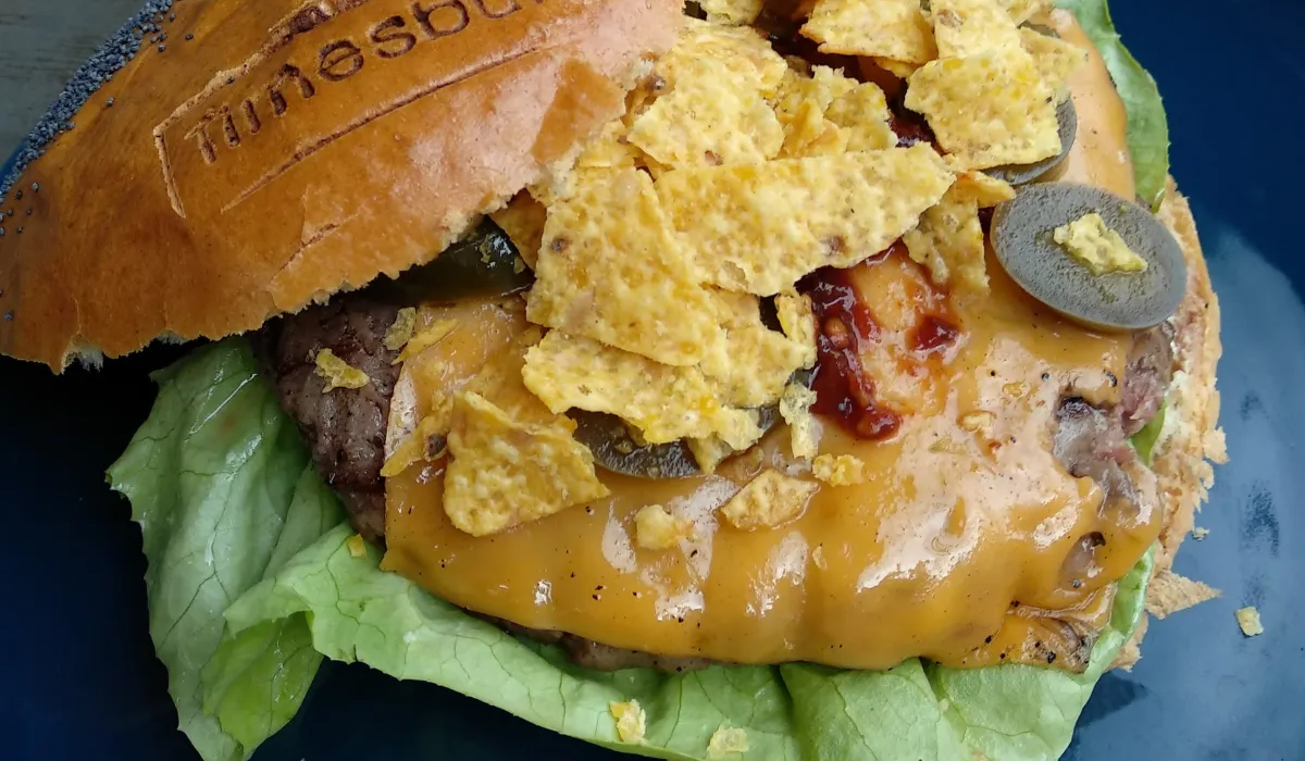 Hamburguesa con cheddar, nachos triturados y jalapeños sobre hoja de lechuga