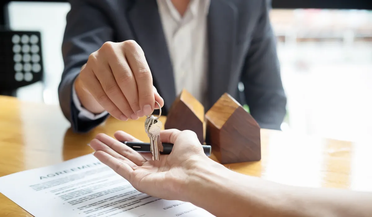 Un agente entrega las llaves de una vivienda sobre un contrato