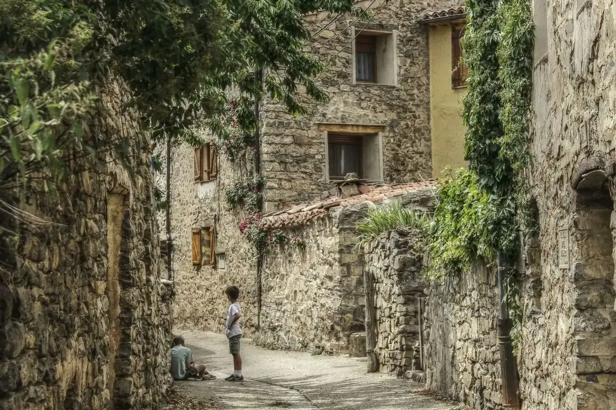 Calle estrecha de casas de piedra con dos niños jugando en Navalsaz