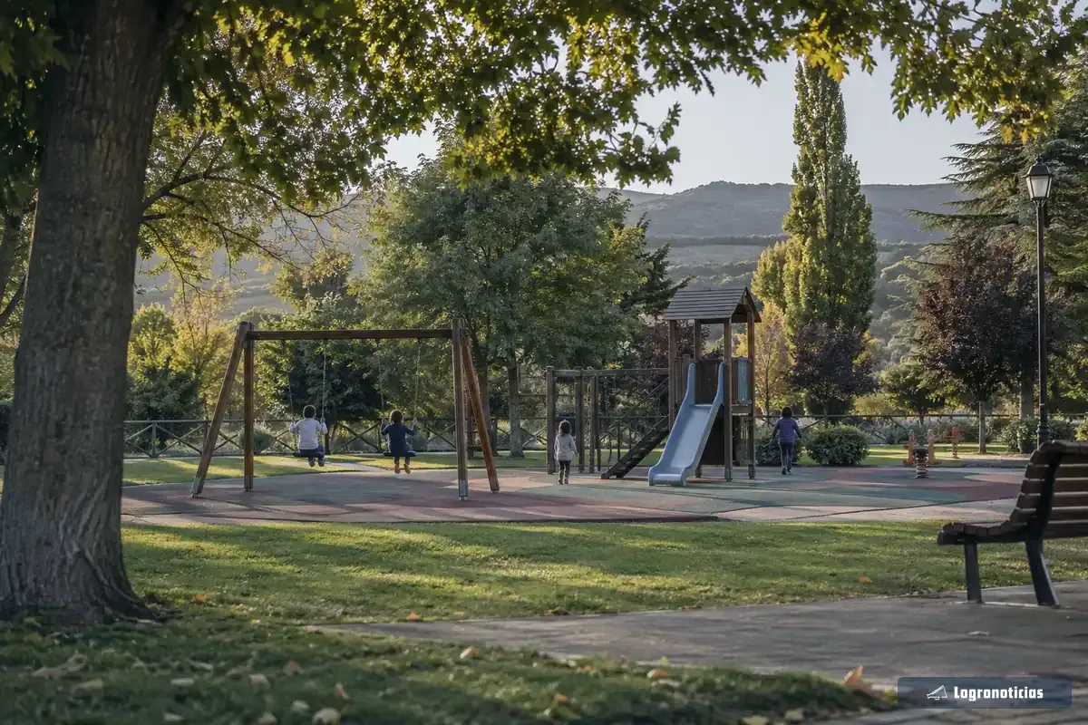 Zona de juegos infantiles con columpios y tobogán rodeada de césped y árboles