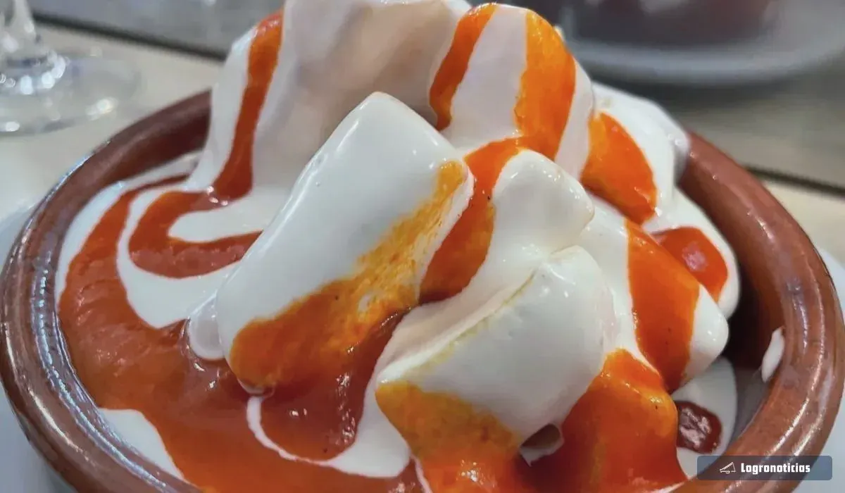 Patatas bravas con salsa blanca y salsa picante en una cazuela de barro