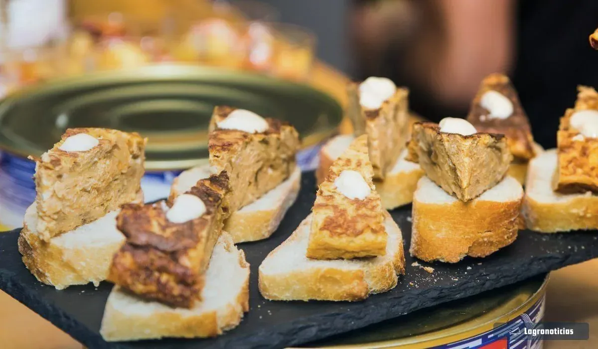 Porciones de tortilla de patata sobre pan en una bandeja de pizarra