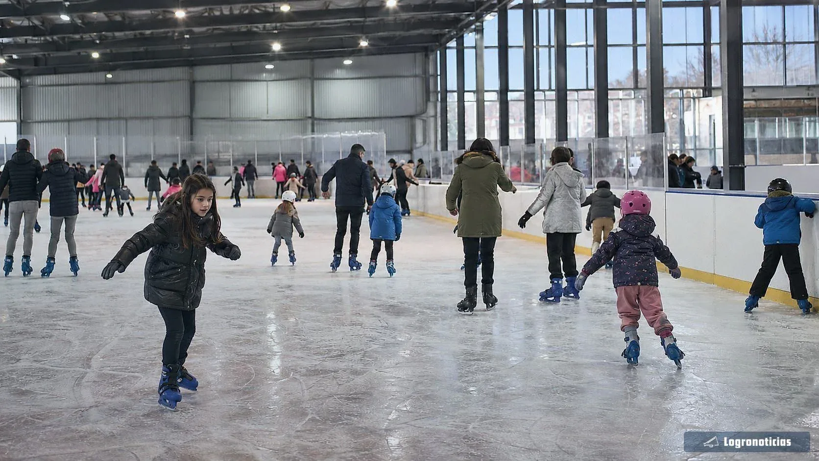 Familias y niños patinando en una pista de hielo cubierta