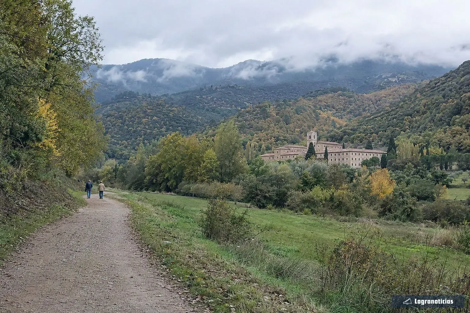 Monasterio de piedra en un valle verde de montaña visto desde un camino