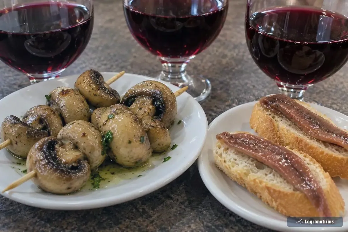 Copas de vino tinto con champiñones en brocheta y tostadas de anchoa en la barra