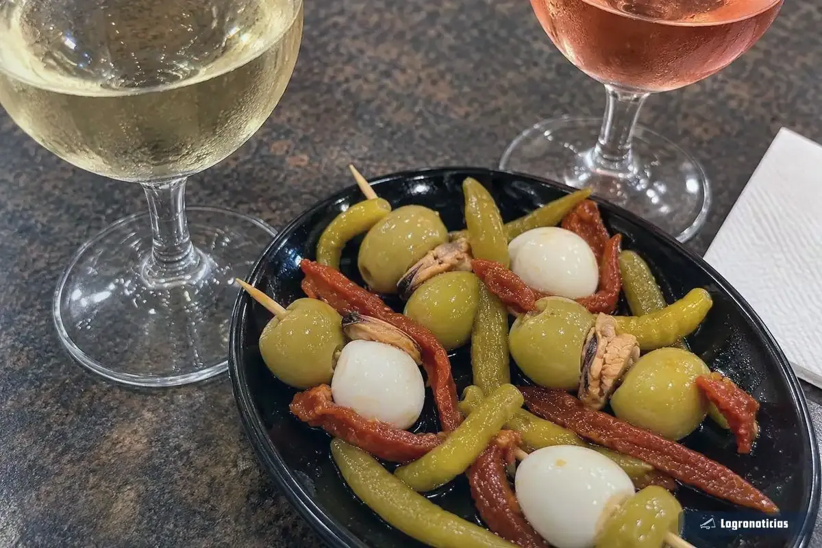 Copa de vino blanco y copa de rosado junto a un plato de banderillas