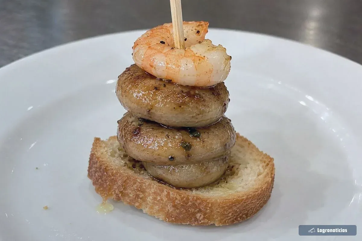 Champiñones apilados en palillo con gamba sobre pan en un plato casero