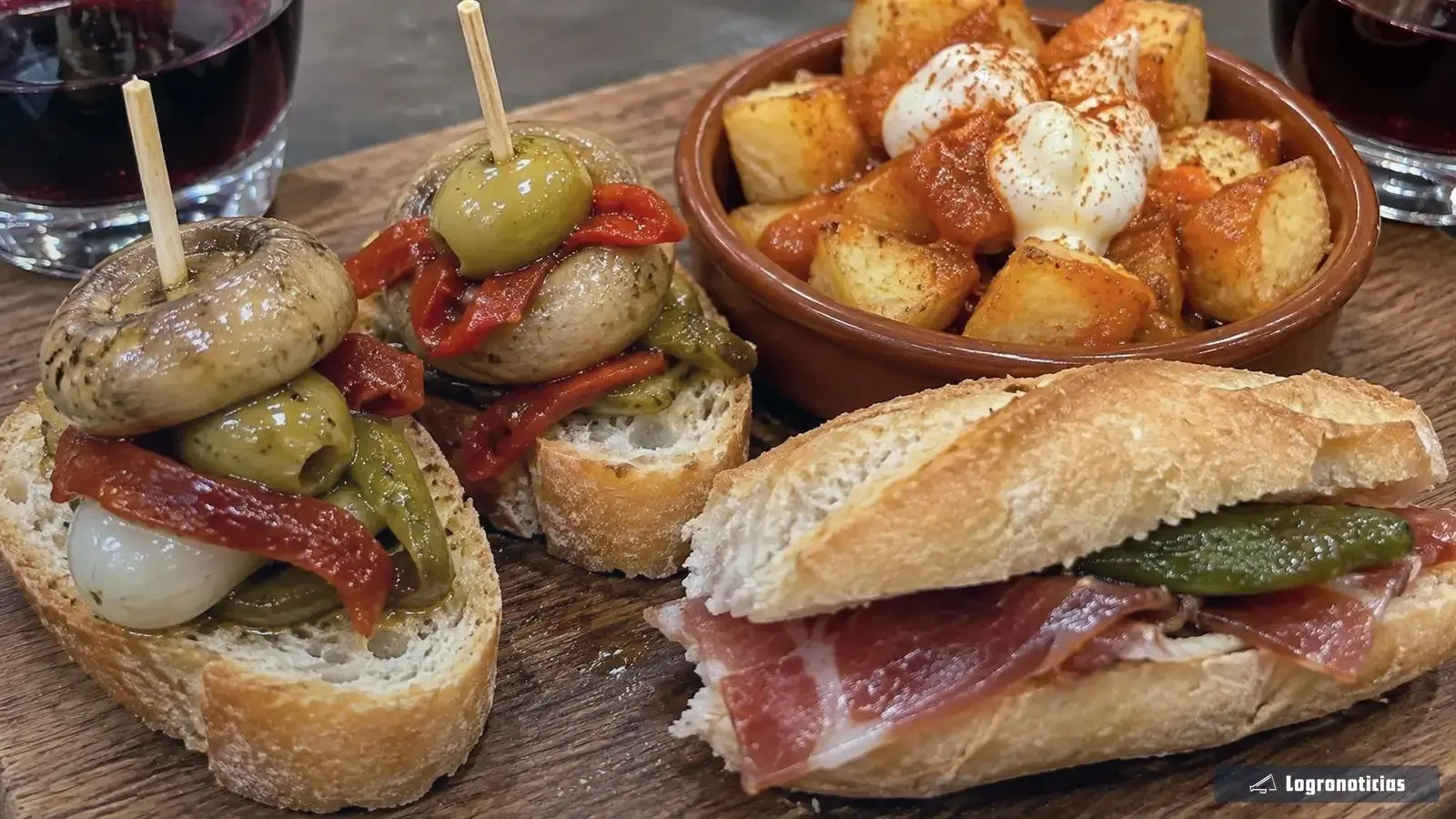Pinchos de champiñones, bocatita y bravas en primer plano con vino