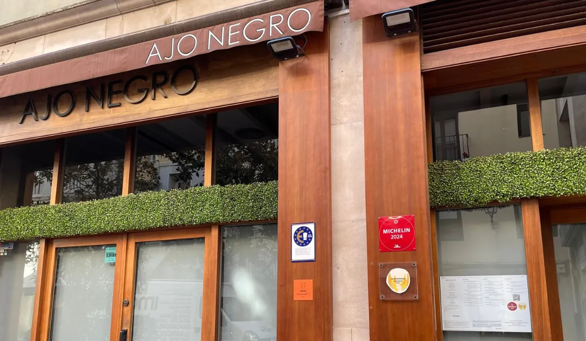 Fachada de madera del restaurante Ajo Negro con seto verde en las ventanas