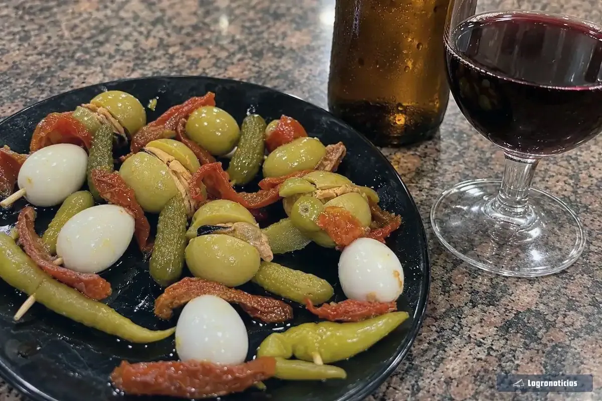 Copa de vino tinto y botellín de cerveza sobre una barra de bar