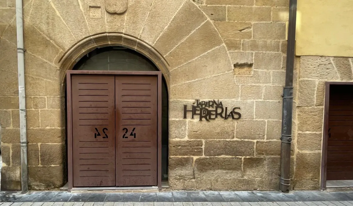 Portón con arco de piedra y rótulo de Taberna Herrerías en el casco antiguo