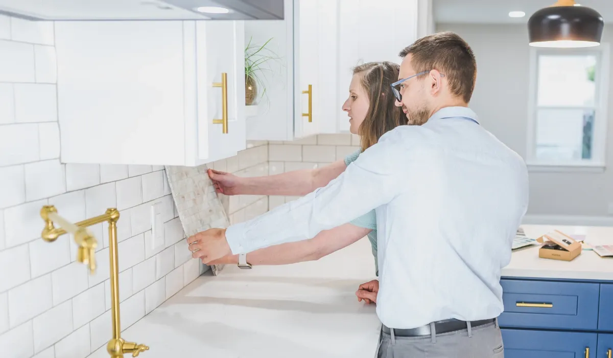 Pareja prueba una muestra de azulejo sobre la encimera de una cocina blanca