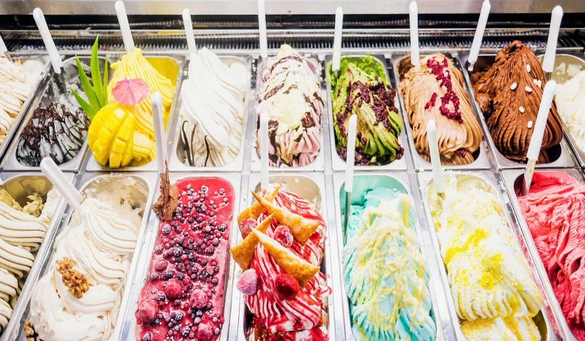 Cubetas de helado de varios sabores decoradas con fruta en una vitrina